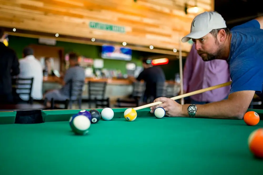 A guest lining up a shot on a pool table at Pflutto's Tavern